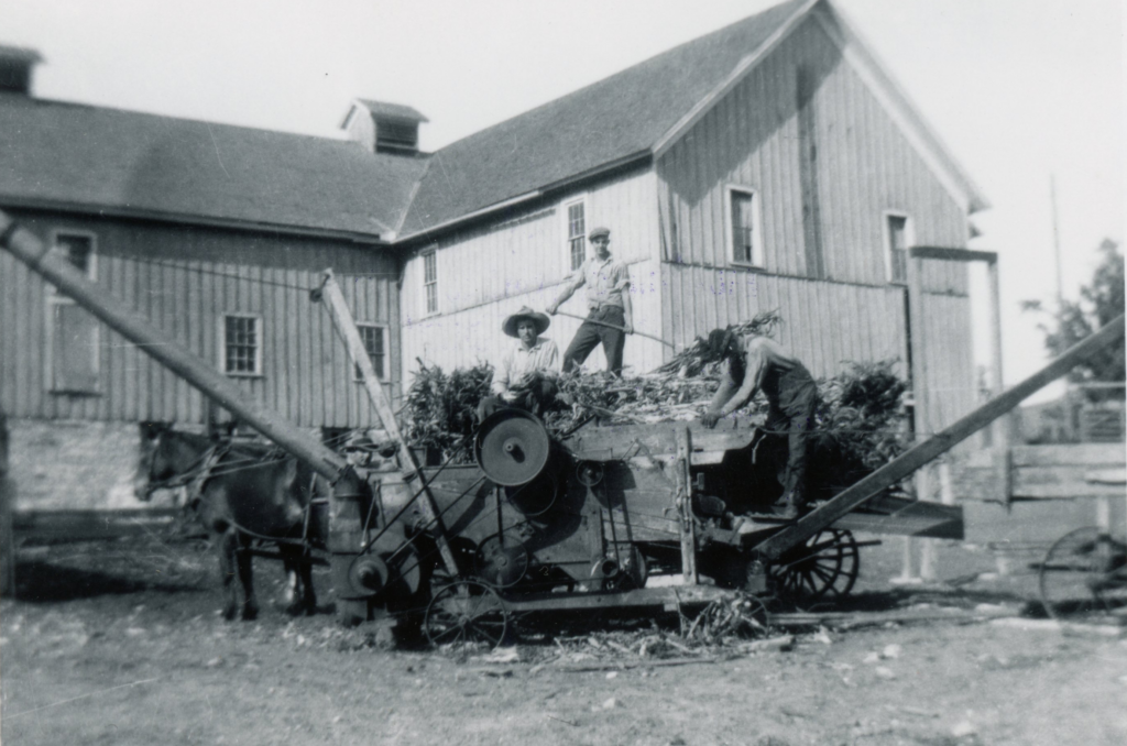 Photo of workers on agricultural thresher at the Hennepin County Poor Farm.